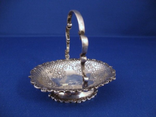 Meyers Rococo Cake Basket: Cake basket with oval body form, scroll and shell molded rim, on similarly molded conforming pedestal foot, the body with floral swags and diaper work around central open base engraved with the initia