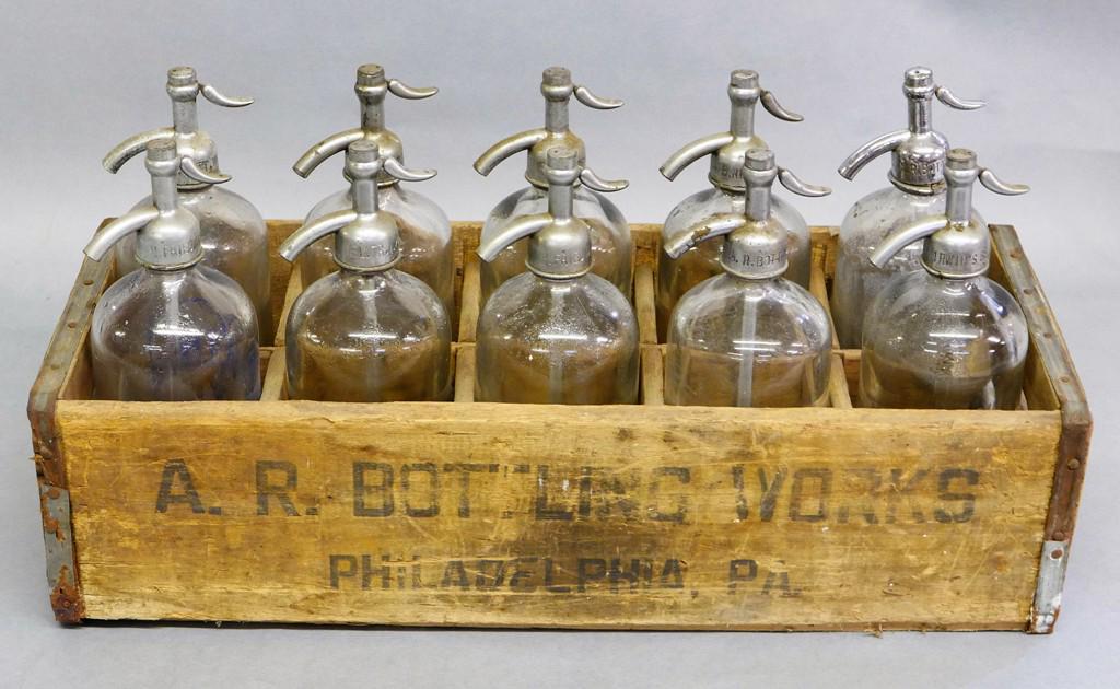 Ten Seltzer Water Bottle & Crate: Group of 10 antique glass advertising seltzer bottles from various makers in Philadelphia, New York and Illinois, housed in a divided wood advertising crate from A.R. Bottling Works Philadelphia 23.5"