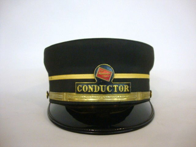 Milwaukee Road Conductor Hat: Milwaukee Road Conductor Hat, with , rectangular Badge with red box logo above, title is raised in gold on black name. Cap is black grosgrain with silver gilt lace band above visor and yellow lace str