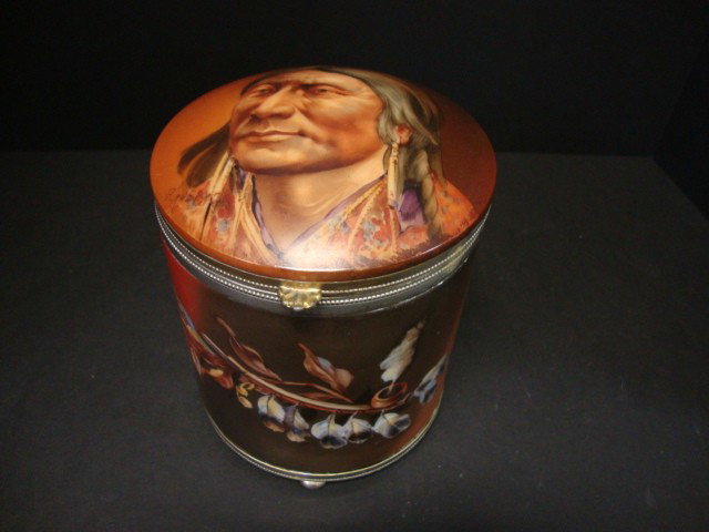 Pairpoint Porcelain Indian Themed Humidor: Tall Humidor Rested on Silver plated base on 4 rounded feet, beveled top contains signed Indian portrait by F.Gubart, front contains painted tobacco pipe decorated with feathers & leaves, all on a med