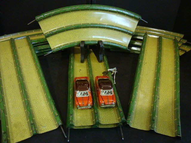 Tin Litho German Wind-up Track with 2 Cars: 1950's German tin litho crossover 2-lane race track w/2 wind-up cars. Cars measure 3" (l), track pieces include crossover bridge haves, 2 straights, 12 curved pieces, wind-up key