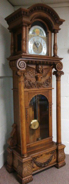 Oak Grandfather Clock: Beautiful brass triple train movement w/moon phase & separate second hand on 2-tone engraved dial, set of 5 chimes with 2 adjustment switches, bonnet is 28" (w) x 28" (h), egg & leaf carving around to