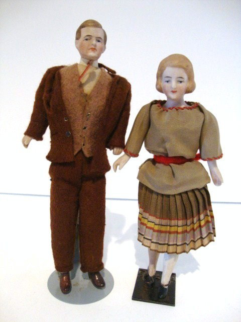 Two Bisque Dollhouse Dolls: Two bisque dollhouse dolls: gentleman in original felt suit with vest and tie #702 6 1/2" H, lady with pleated skirt and red sticking on blouse, 6 1/2" H # 608, retaining her original stand.