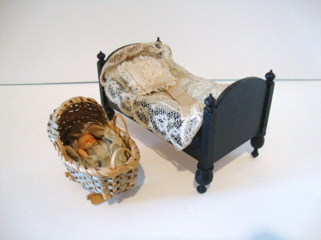 Waltershausen Bed and a Cradle: A small German bed 5" L with antique bedspread and pillow and charming woven basket cradle with small bisque baby inside and marked Germany.