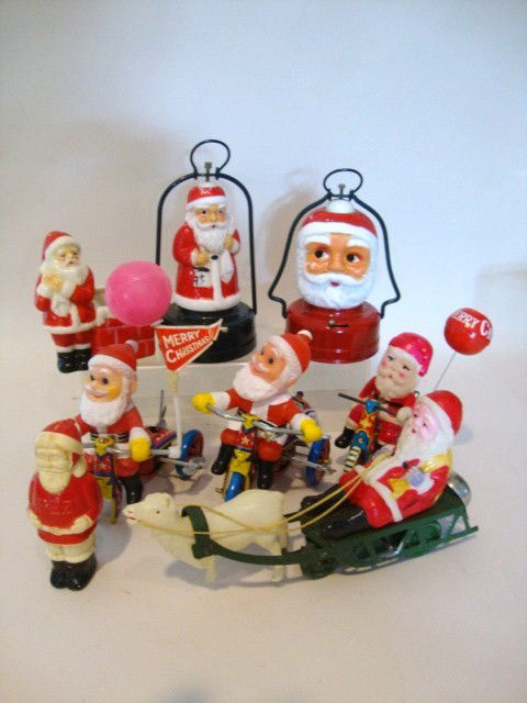 Large Santa Claus Lot: Eight miscellaneous Santas including 3 wind-up Santas on tricycles, 2 Santa lights, celluloid wind-up Santa on Sleigh, early Santa Pez container, ceramic Santa at Chimney, 8 pcs. total 8" (l) x 7" (t)