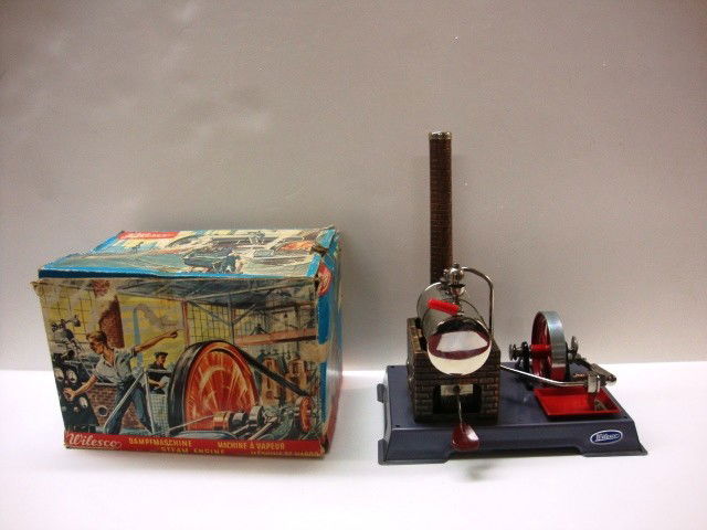 Wilesco D5 Operating Steam Engine w/Original Box: An Operating Steam Engine by Wilesco Model D5 with the OB. Steam Engine sits on metal base that measures 8" x 5 1/2" x 5/8" (h), with steam engine standing 6" (h), there is a smoke stack that brings t