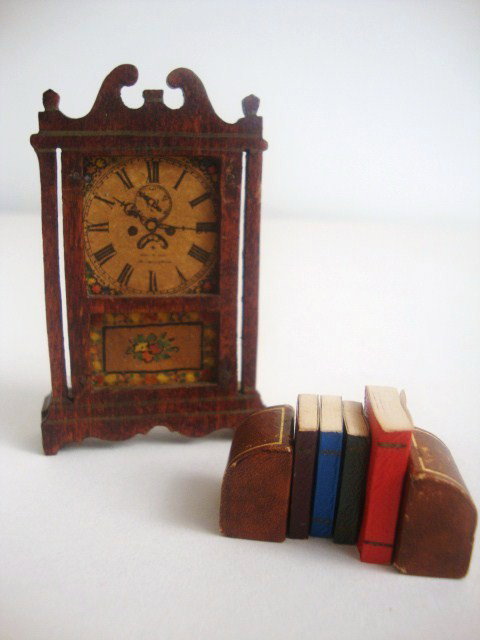 Tynietoy Terry Clock and Books: Vintage Tynietoy Eli Terry mantel clock, stamped on the back, paper darkened with age, modern paper-covered books and a pair of vintage heavy leather-covered bookends. Clock 3" H.