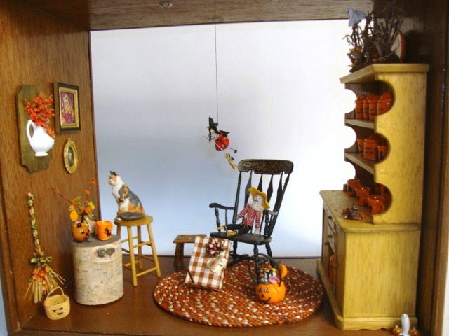 Halloween Roombox: A double-sided roombox 10" L, 9" H, 6" D furnished with a fun assortment of holiday decorations, a hutch filled with theme cups and plates, a rocker, braided rug and numerous accessories.