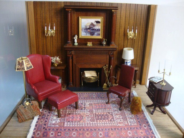 Formal Parlor Roombox: A three-sided roombox 14" L, 10.5" D and 11.5" H furnished with traditional red leather seating by d. Anne Ruff, commercial paneled fireplace and tables, electrified lamps and accessories.