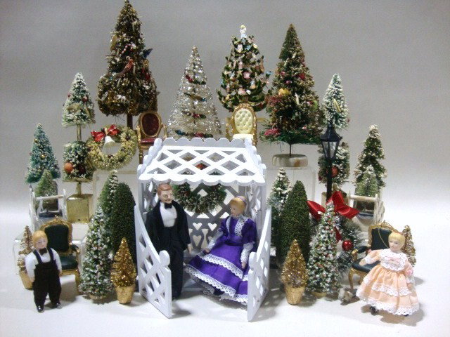 Christmas Tree Fantasy: A vignette comprised of over a dozen vintage and more recent Christmas trees and other miniature decorations including a wreath, sleigh, chairs and a couple under an latticework arbor.