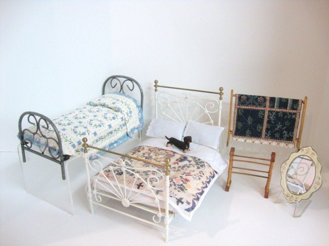 Robert Carlisle Metal Bed: An ornate painted cast iron bed 7" L, 6" H, 4.5" W by Robert Carlisle with bedding, a single iron bed, a quilt rack and towel rack by other artists, a pretty painted mirror and a dachshund.