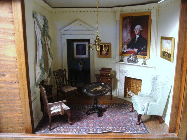 Virginia Parlor Roombox: Virginia parlor roombox with corner fireplace, rear hallway, wonderfully detailed window with fancy draperies and a view of Monticello, furnished with an upholstered wing chair, pair of carved side ch