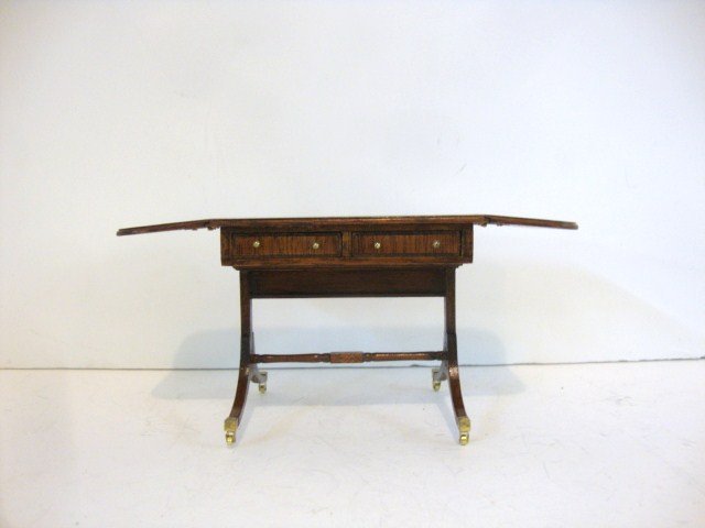 Dennis Jenvey Sofa Table: Mahogany Regency sofa table with hinged leaves at each end, brass casters and satinwood banding. Drawers open on one side only. 2.5" H, 3.25" W.