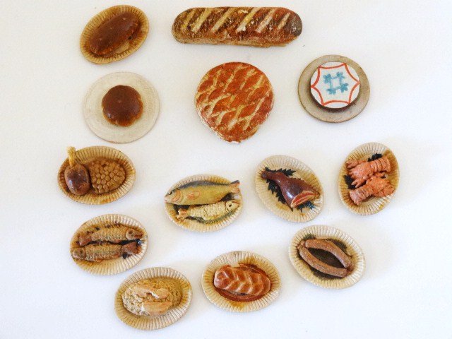 Antique Food Platters: An assortment of ten cardboard plates 1.25" L with painted plaster foods including fish, lobsters, sausages, breads, a pretty decorated cake on a card plate and two painted plaster baked items.