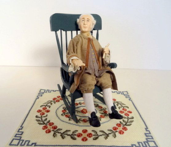 Shirley Whitworth Colonial Gentleman: A very nicely dressed older character doll holding a document. Stands 6" H, head is jointed, detailed costume. With an unsigned wooden Boston rocker and an embroidered rug.