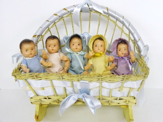 Complete Set of Dionne Quintuplet Dolls: Complete set of 6 Dionne Quintuplet dolls, w/original clothing, 2 missing hats, all w/new ribbons in vintage cradle w/new ribbons 13 x 14 in. (Dorothy Huber Collection)