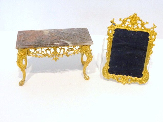 John Hodgson Mirror and Table: Classic gilt metal Chippendale console table with mottled marble top 3" H, 2" D and 5" W and a gilt mirror. Adhesive residue.