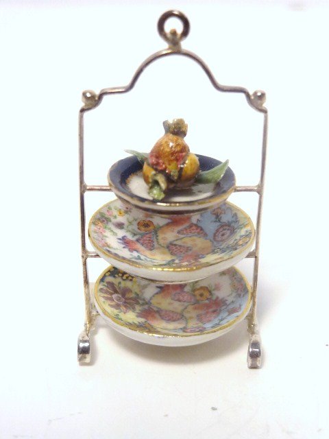 Le Chateau Dessert Caddy: A sterling three-tiered plate stand by Enrique Quintanar embellished by Jeff Gueno and Frank Hanley with hand-painted porcelain plates and pomegranates. Yummy in every way imaginable. 1.75" H.