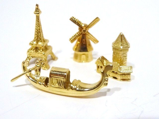 Bucherer 14 KT Gold Miniatures: Windmill, Eiffel Tower, gondola, tower bridge, all in original boxes, unmarked but test gold, all between 1/2 in. to 3/4 in. (T) The gold weight is 7.5 Grams