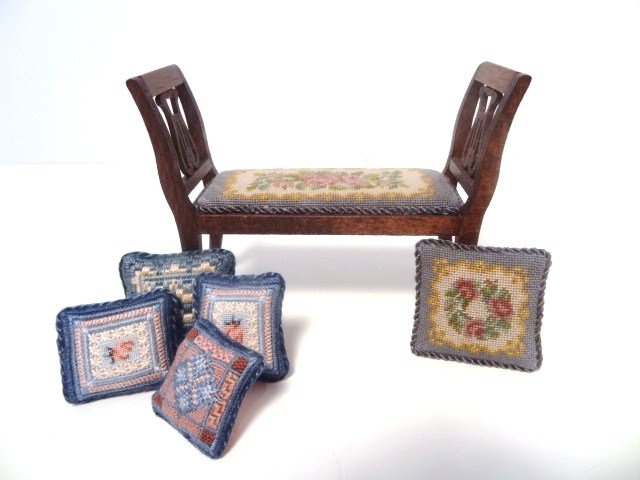Petitpoint Bench and Pillow: A classical bench or window seat upholstered with fine petitpoint 2.75" H, 3.75" L, with a matching pillow and assortment of four additional petitpoint pillows. Finely stitched and finished.