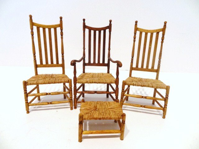 Linda Phelps Country Chairs: A set of three early American rush-seat chairs just over 4" H and a matching footstool. The armchair features unusual arms with pierced hand rests where a bar can be run through. Some joints reglued.