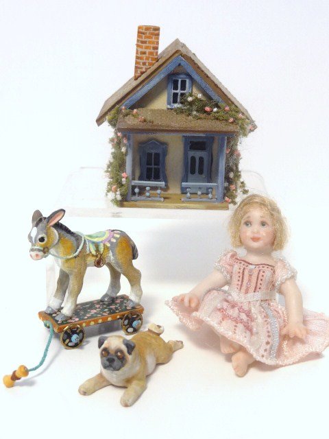 Amanda Skinner Girl and Toys: A charming little bisque girl with jointed limbs 2.25" H in a nicely detailed pink dress along with a tiny dollhouse cottage rich with decorative features, a little pug dog and a donkey pull toy, all