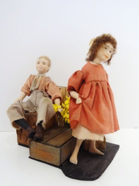 Shirley Whitworth "Young Love": A one-of-a-kind rag-tag pair of country children glued into a vignette with empty crates and daffodils. The girl is just under 4.5" H, the boy is lovesick and gathering his courage to present her with