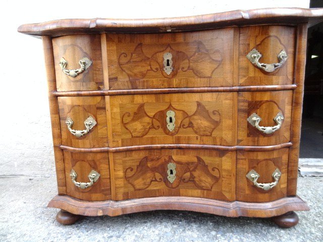 Dutch Marquetry Baroque Style Commode: Circa 1850 the overlaying cross band molded serpentine top panel over 3 serpentine drawer fronts w/vine & geometric design marquetery in various colored woods sitting on bun feet, top inlaid in variou