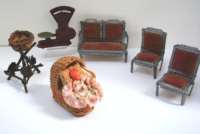 Cast Iron Scale and Metal Furniture: A Toledo cast iron scale 4" H and W with minimal paint wear, a soft metal parlor suite with faded velvet upholstery, the settee 3.5" H, 5" W, a celluloid baby in a wicker crib and a neat little twig s
