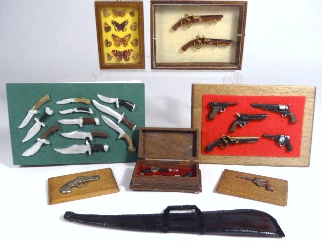 Guns and Knives: Assortment of knives and pistols in display cases or wall mounts, a set of cast metal dueling pistols in a case, a soft gun case and a display case of butterflies. Ron Stetkowicz made the pistols in t
