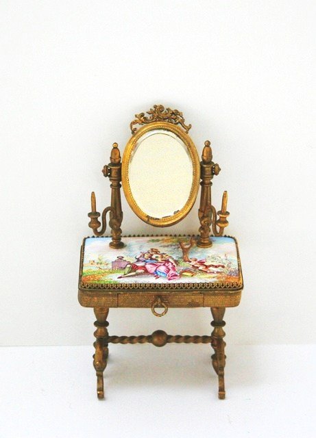 Gilt Enameled Dressing Table: An exquisite 1/12" scale unmarked gilt metal dressing table with hand-painted porcelain enamel table top, an attached oval mirror with swivel candlesticks and a pull-out drawer. The back of the mirror