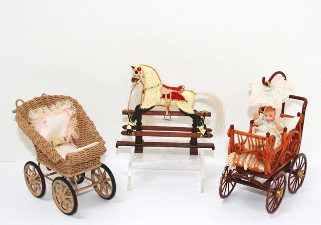 Prams and Rocking Horse: An English rocking horse on gliders 3.5" H, 3.75" L made in England for The Singing Tree, a natural wicker pram by G. Taylor with leather trimmed wheels, and a rattan and metal pram with infant marked
