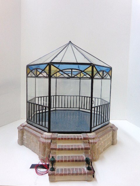 Stained Glass Gazebo: Handcrafted by Lady Jane, an octagonal gazebo encased in clear and stained glass, set upon an ashlar stone base and steps with electrified footlights. The floor is a single piece of dark pebbled glass