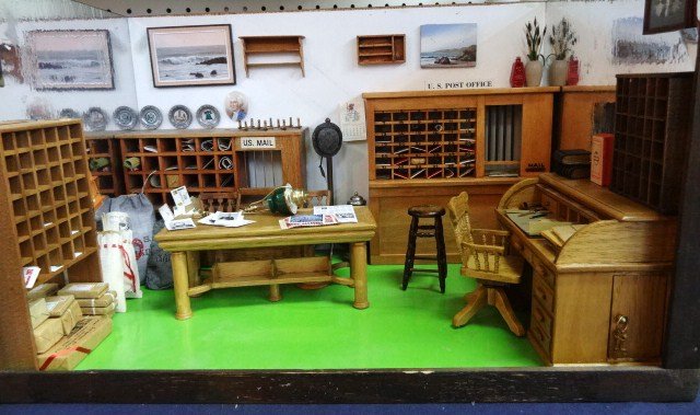 Post Office Roombox: A roombox designed as a small old-time post office with sorting cabinets, numbered PO boxes, bags of letter, packages tied with string, roll-top desk, oil stove, etc. 14" H, 16" W, 11 D.