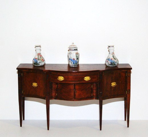 Lou Murter Sideboard: Elegant mahogany Hepplewhite sideboard with serpentine front and hand-carved details. 3.25" H, 6" L. With Bespaq garniture.