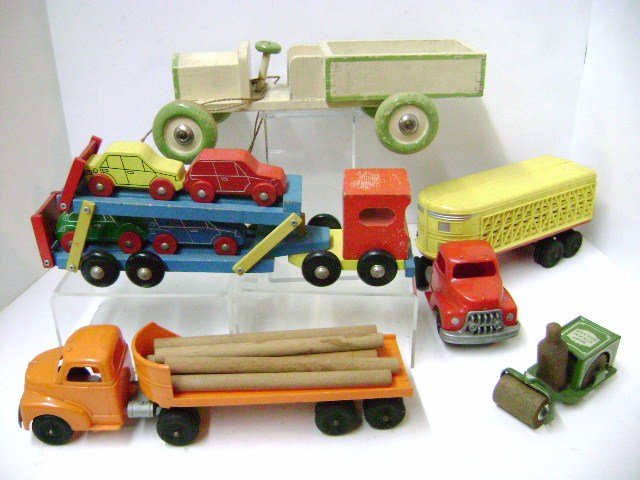 Pair Hubley Trucks and Other Vehicles: Hubley plastic log hauler 12" L, Hubley cattle hauler 12" L, wood auto hauler with four cars 13" L, Husa wood truck 13" L and an early Animate Toy Hobo Baby Steam Roller 4.5" L