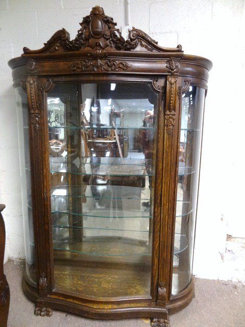 Carved Oak China Cabinet: Ornate 19th century oak china closet, paw feet w/curved glass sides & ox bowed front door glass, 4 glass shelves w/mirrored back, applied carving w/medallion ribbon flowers & broken arch pediment, 53"