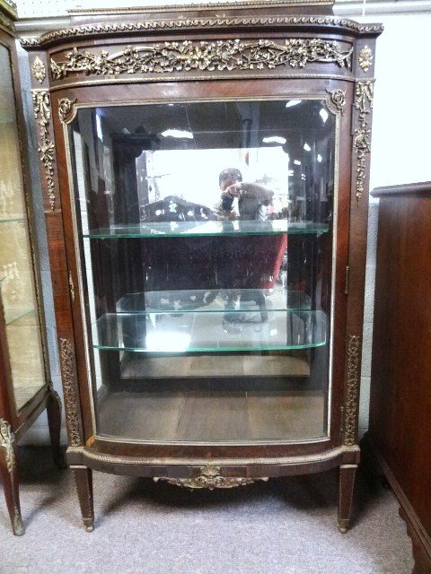 Early French Vitrine: Early French vitrine, mahogany veneer, case w/marble top, extensive ormolu mounts, bow front, glass sides, interior w/two glass shelves & mirrored back, 54 in. (h), 31 in. (w), 15 in. (d)