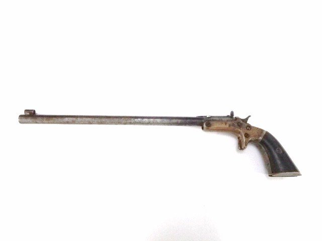 Stevens 1864 Single Shot: Very early Stevens tip up .22 caliber target pistol, 3 digit serial number, brass frame w/walnut grips, 10 in. barrel w/hooded front sight, screw adjustable rear sight, bottom on butt slotted for shou