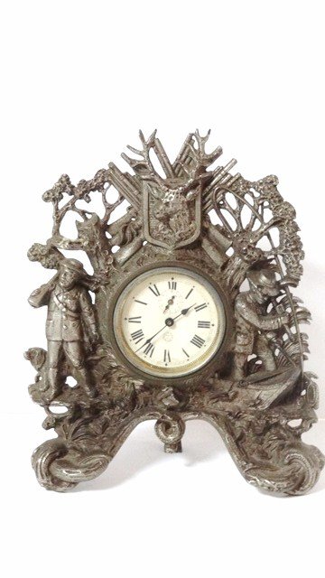 French Figural Hunting Clock: Armes E.T. Cycles Saint Etienne France figural alarm clock, wind-up movement w/alarm & exposed escapement on rear, iron case w/nickel plating, depicts hunter & dog, guns, game & fishermen, 13 in. (h)