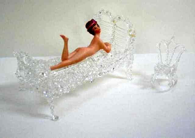 Antique Bisque Bathing Belle Doll: Reclining bisque lady with flapper hairstyle 4.5" L, faint marking on belly, surface dirt but no broken toes or fingers. Reclining on a blown glass bed 6" L (repaired) and a small glass rocking chair.