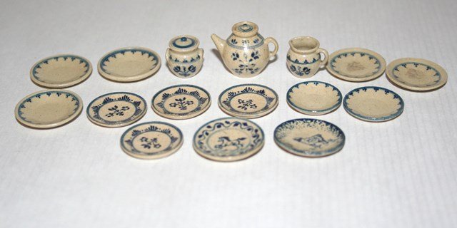 Jane Graber Plates: An assortment of thirteen 1" scale stoneware plates 7/8" diameter and a tea pot with lid, creamer and sugar. MK