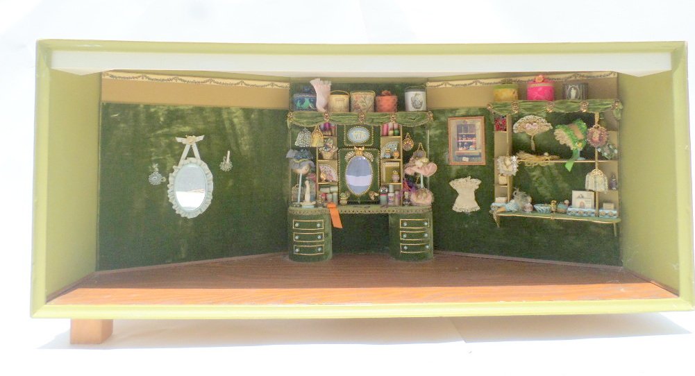 Millinery Roombox: A large velvet upholstered roombox partially furnished as a dressing room or milliner's with elaborately festooned vanity and wall shelves filled with hats, hatboxes, beaded bags, toiletries, dress pa