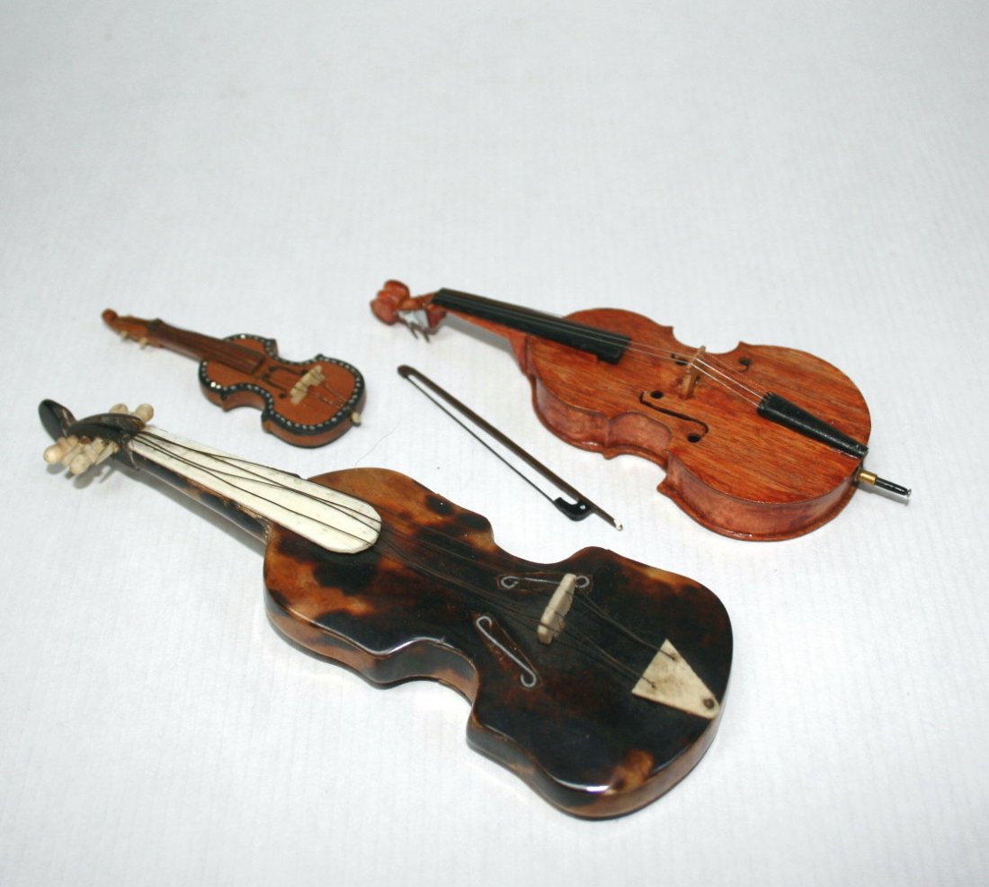 Dollhouse Miniature Cello and Violins: A nicely detailed artisan cello 5" L with bow, a doll-sixe tortoiseshell violin with bone tuning pegs 6" L, and a small wooden violin with the back decorated with moth-of-pearl inlays - very pretty.
