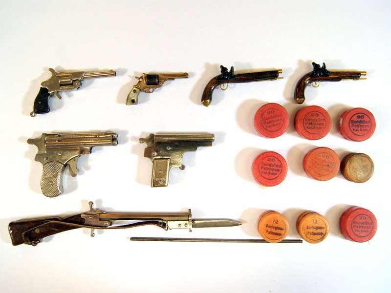 4 Miniature Working Guns and Others: Breech loading military pinfire rifle with bayonet, sling and wood stock signed Austria 5 1/3"L about 2mm bore, breech loading single shot pinfire pistol by JMF Co circa 1930's with molded grips, 2"L,
