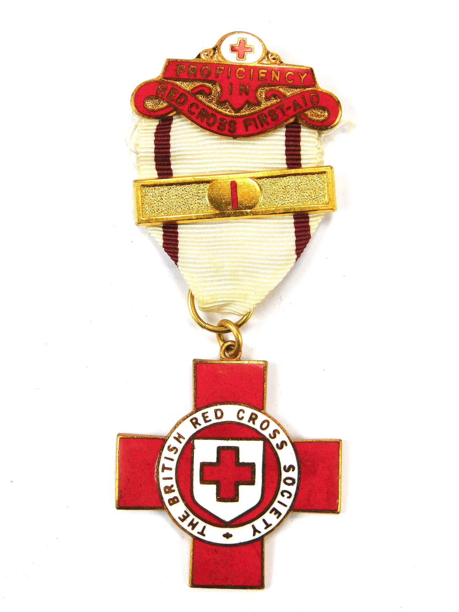 British Red Cross Society Proficiency in Red Cross First Aid Medal with “1” Bar: In-House Shipping. British Red Cross Society First Aid Proficiency medal with enamel cross and original “1” year bar. Gilt metal with red and white enamel, original ribbon and pinback. Ear