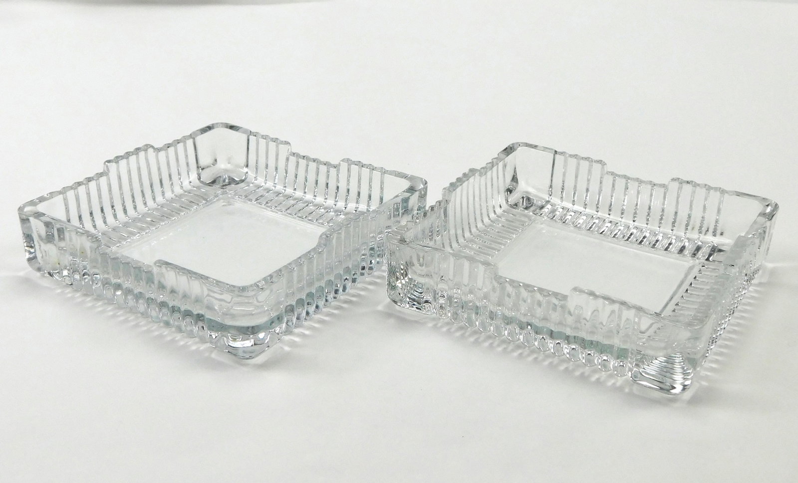 Set of 2 Vintage Heavy Clear Pressed Glass Square Ashtrays Ribbed Sawtooth Edge: In House Shipping. Set of two vintage heavy clear pressed glass square ashtrays featuring thick substantial construction, ribbed geometric detailing and textured sawtooth-style rims. Each is designed 