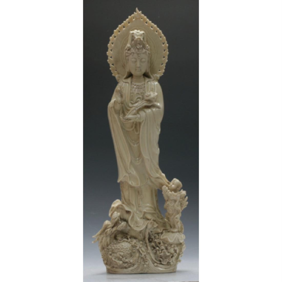 A Very Large De Hua Guan Yin Figure: Guan Yin holding Ling Zhi sceptre and a child linked to her clothing standing on a sea animal. H: 63cm