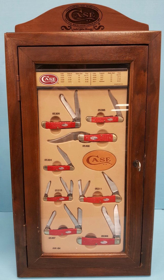 Case Knife Display with 8 American Flag Case Knives: A set of 8 red American flag Case knives with wood display case. The display case has a slant front with plexiglass window to show the knives and wood trim. there is a handsome solid wood topper with