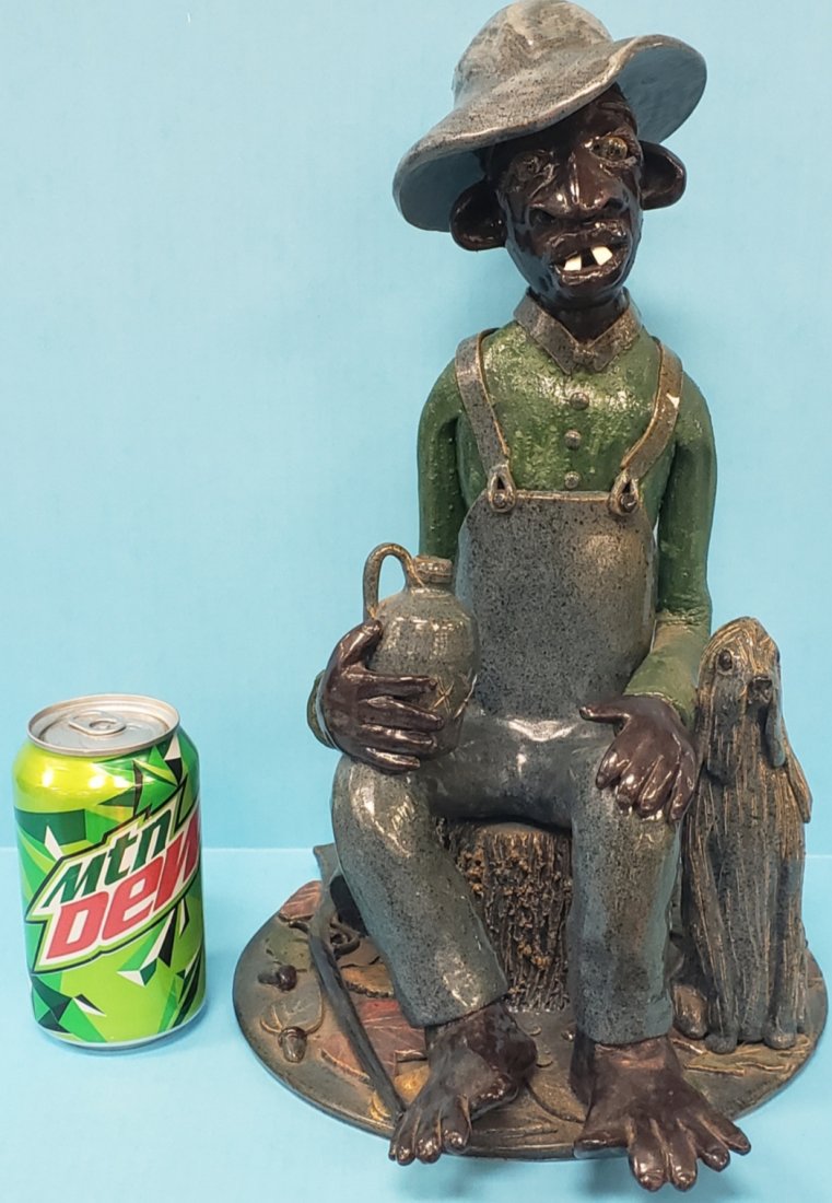 Lin Craven Black Americana Folk Art Pottery: 14.5"h Detailed scene with black man in overalls and hat sitting on a stump holding a whiskey jug with another on the ground, including a shotgun, racoon, dog, and fall foliage on the ground. This pie